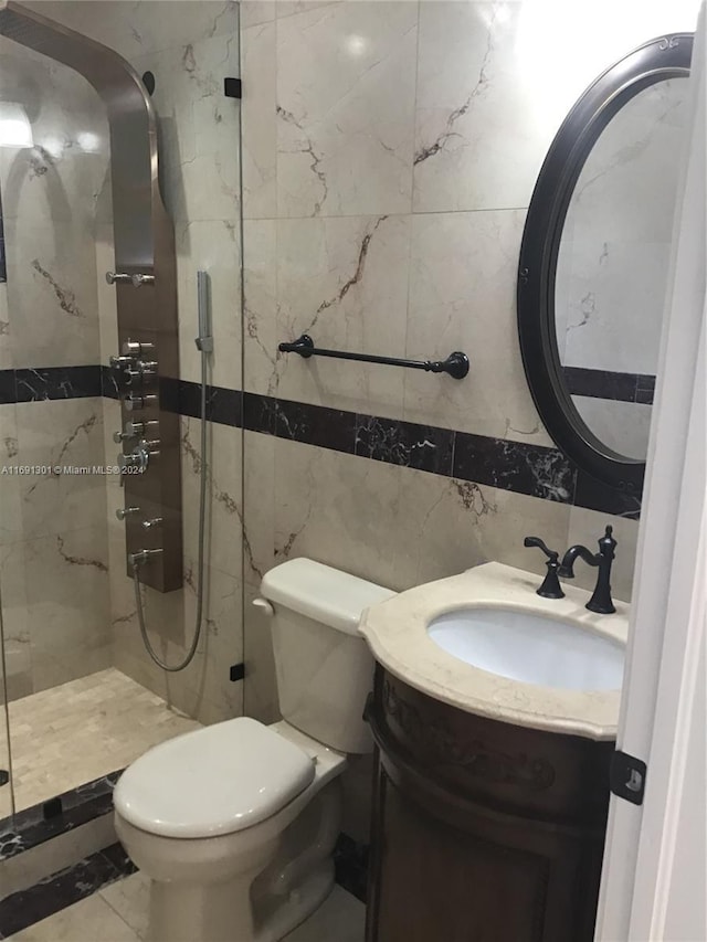 bathroom with vanity, toilet, tiled shower, and tile walls