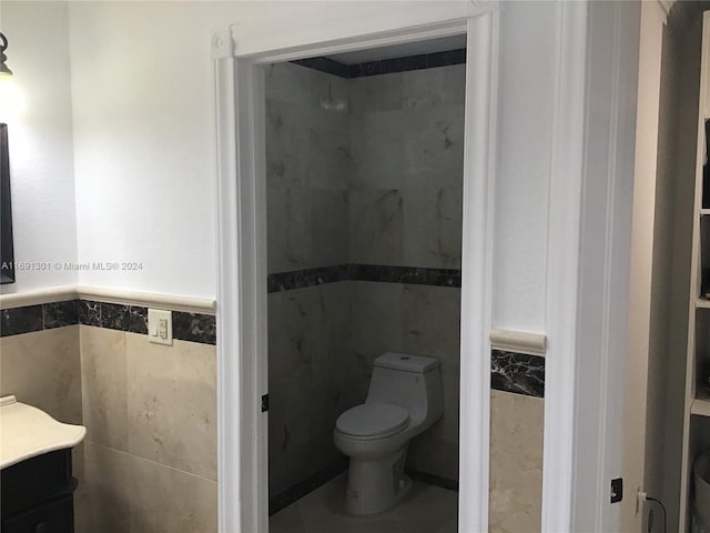 bathroom featuring vanity, toilet, and tile walls