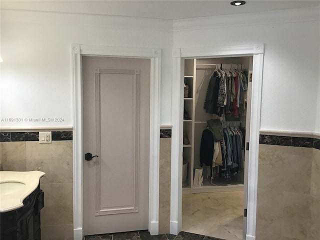 bathroom with vanity, crown molding, and tile walls