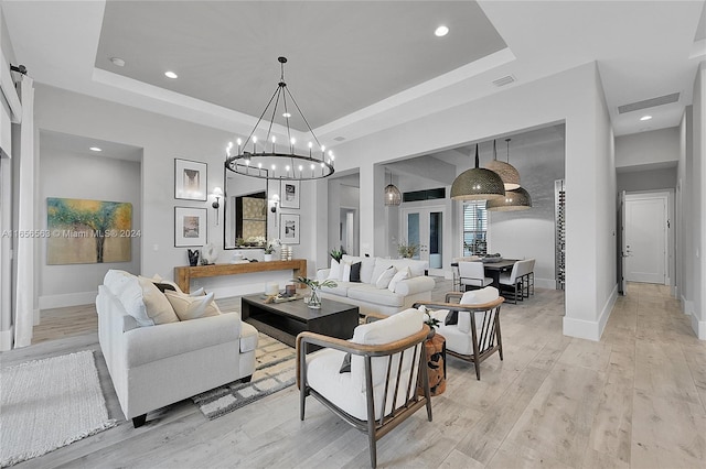 living room with light hardwood / wood-style floors, a chandelier, and a tray ceiling