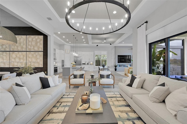 living room with a raised ceiling, light hardwood / wood-style flooring, and a notable chandelier