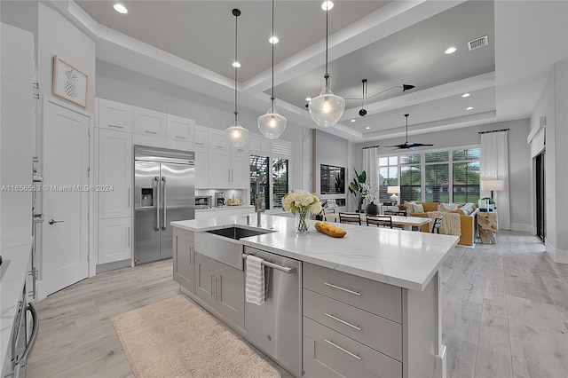 kitchen featuring stainless steel appliances, a large island, decorative light fixtures, and a tray ceiling