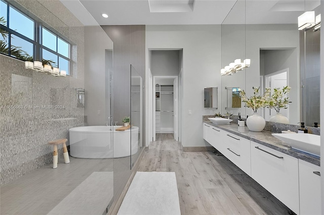 bathroom with a bathtub, vanity, wood-type flooring, and tile walls