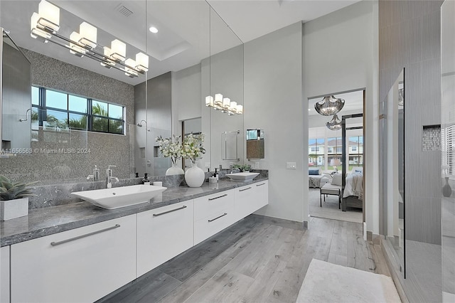 bathroom with a healthy amount of sunlight, a towering ceiling, vanity, and hardwood / wood-style flooring