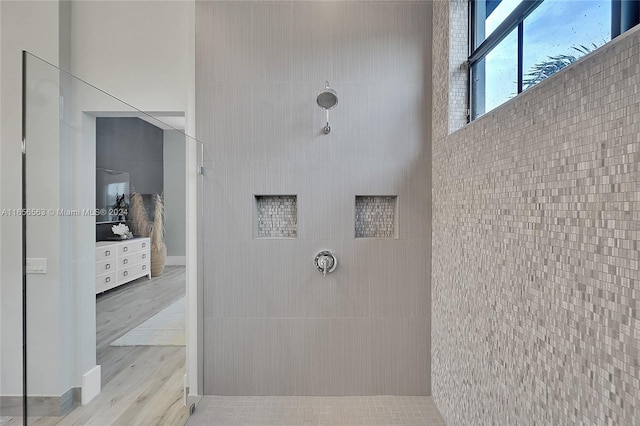 bathroom with hardwood / wood-style floors, walk in shower, and tile walls