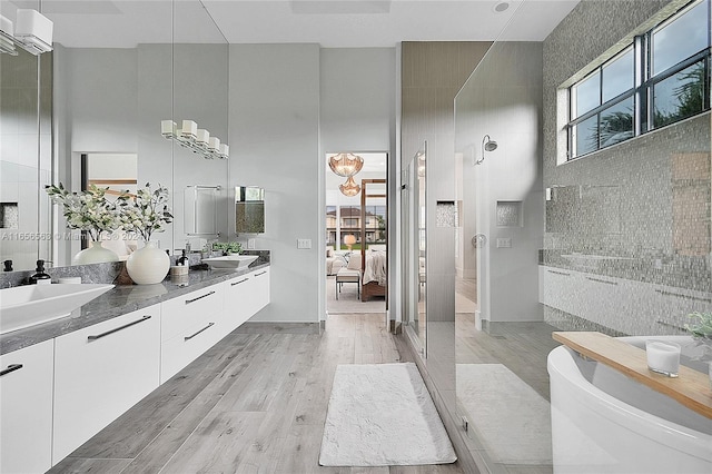 bathroom featuring tile walls, hardwood / wood-style floors, a towering ceiling, vanity, and a shower with shower door