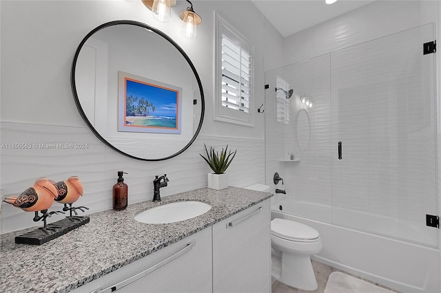 full bathroom with enclosed tub / shower combo, vanity, and toilet