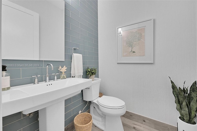 bathroom with tile walls, hardwood / wood-style floors, and toilet