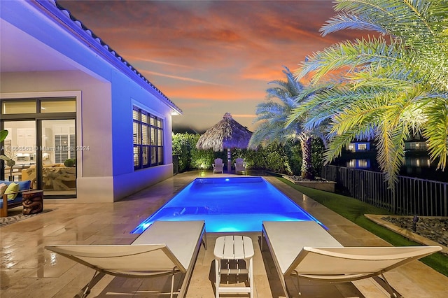 pool at dusk with a patio area