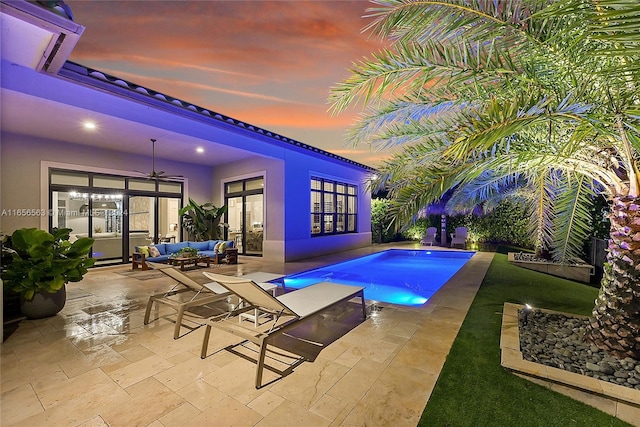 pool at dusk featuring a patio and an outdoor living space