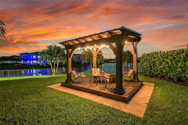 exterior space with a deck with water view, a lawn, and a pergola