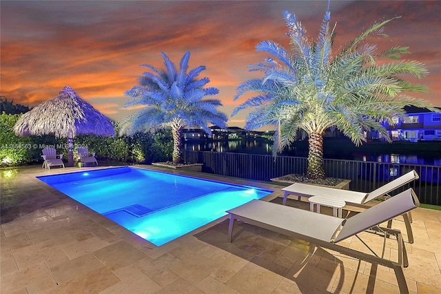 pool at dusk with a patio area