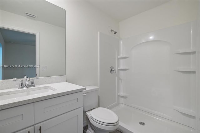 bathroom featuring vanity, toilet, and walk in shower