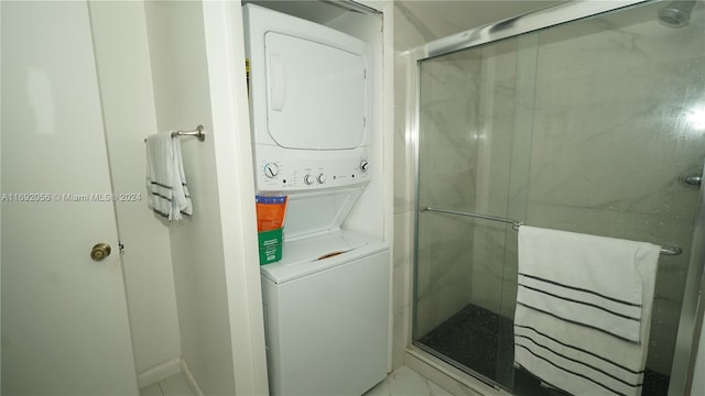 bathroom featuring stacked washer and clothes dryer and a shower with door