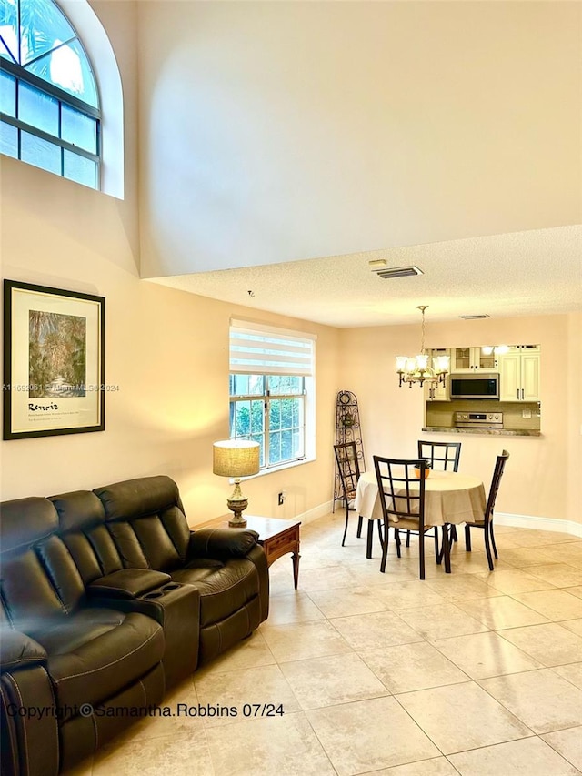 living room with a notable chandelier, light tile patterned floors, and a textured ceiling