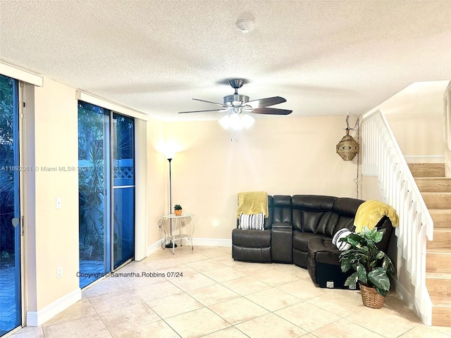 living room with ceiling fan, light tile patterned flooring, and a textured ceiling