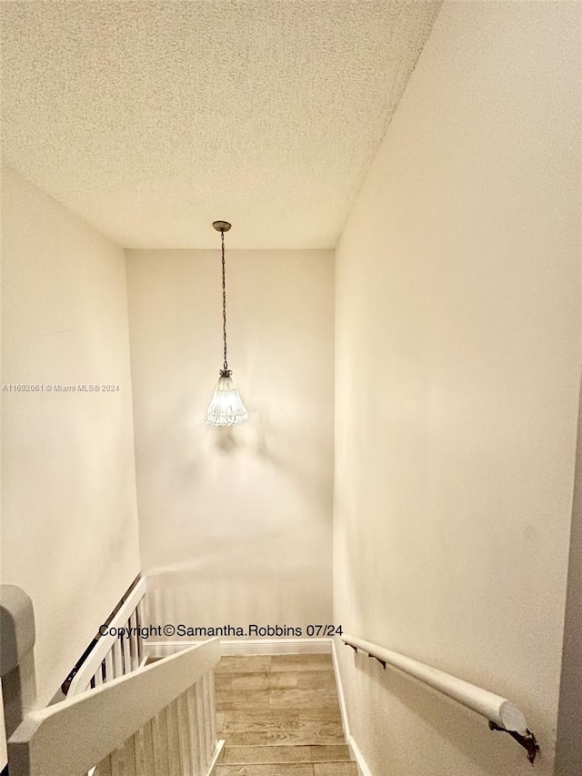 stairway featuring a textured ceiling and hardwood / wood-style flooring