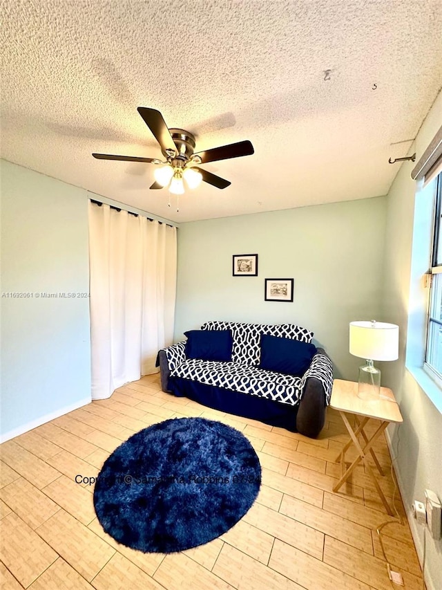 living area with ceiling fan, light hardwood / wood-style floors, and a textured ceiling