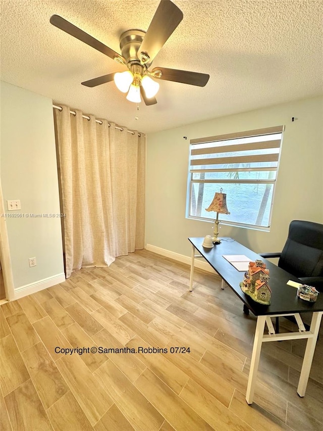 living area featuring hardwood / wood-style flooring, ceiling fan, and a textured ceiling