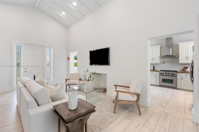 living room with beamed ceiling, high vaulted ceiling, and light wood-type flooring