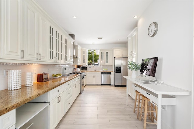 kitchen featuring sink, light stone countertops, tasteful backsplash, white cabinetry, and stainless steel appliances