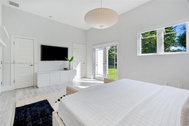 bedroom with multiple windows, french doors, light hardwood / wood-style floors, and access to exterior