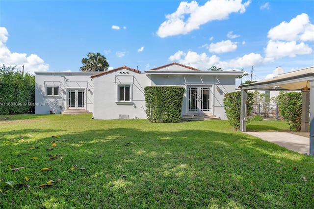 back of house with french doors and a lawn