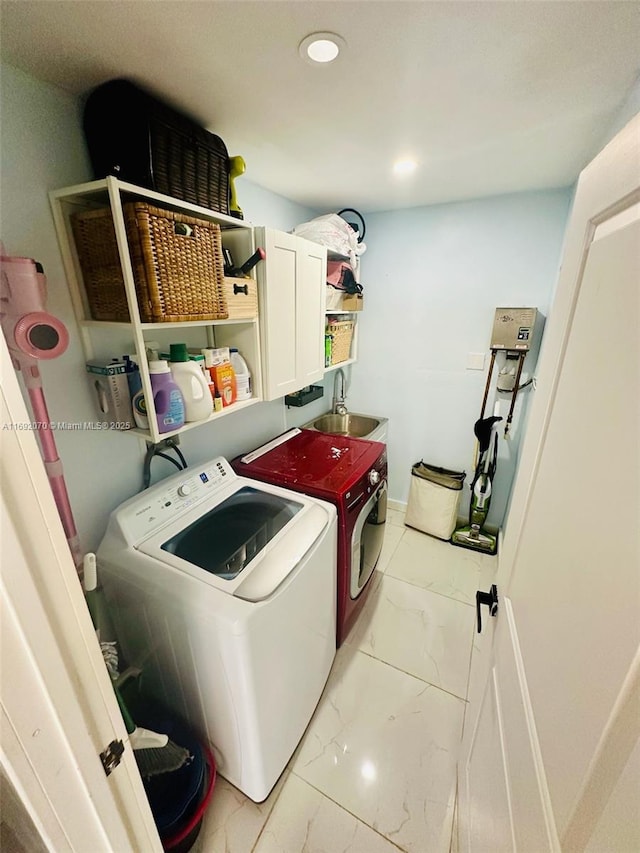 laundry room featuring sink, washing machine and clothes dryer, and cabinets