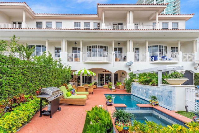 rear view of property featuring a patio area and a swimming pool with hot tub