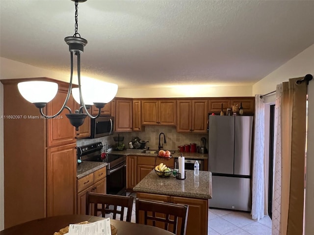 kitchen with backsplash, appliances with stainless steel finishes, hanging light fixtures, sink, and a center island