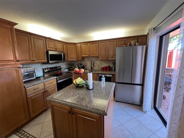 kitchen featuring light tile patterned flooring, appliances with stainless steel finishes, a textured ceiling, a center island, and decorative backsplash