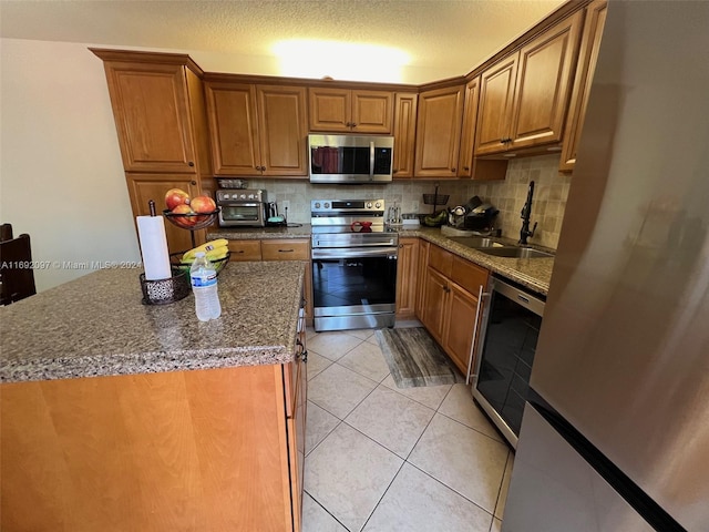 kitchen featuring decorative backsplash, a textured ceiling, sink, appliances with stainless steel finishes, and dark stone countertops