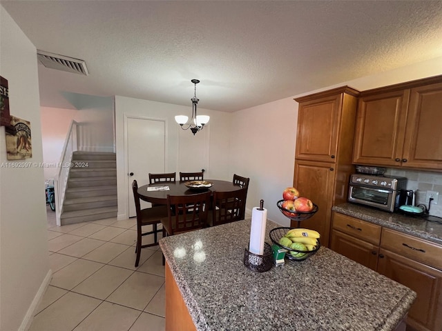 kitchen with light tile patterned flooring, decorative light fixtures, a textured ceiling, a chandelier, and a center island