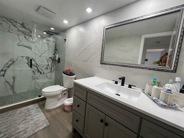 bathroom featuring hardwood / wood-style floors, vanity, an enclosed shower, toilet, and tile walls