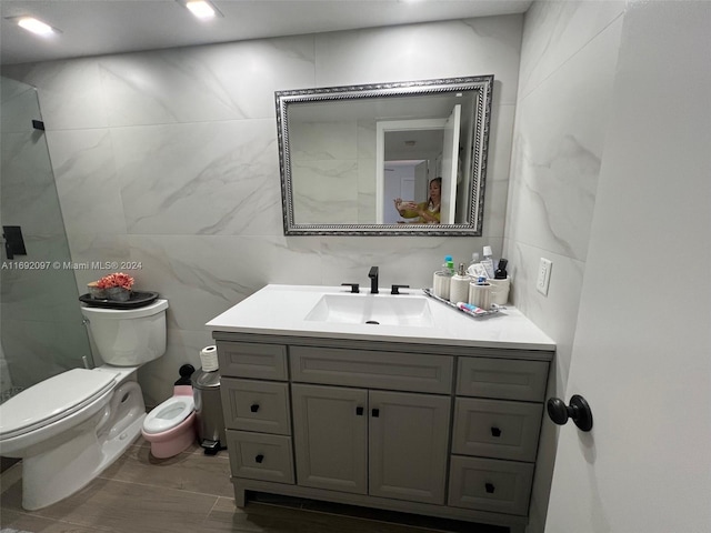 bathroom with tile walls, vanity, and toilet