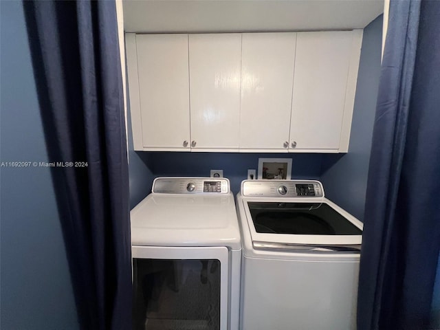 laundry room featuring washing machine and clothes dryer and cabinets