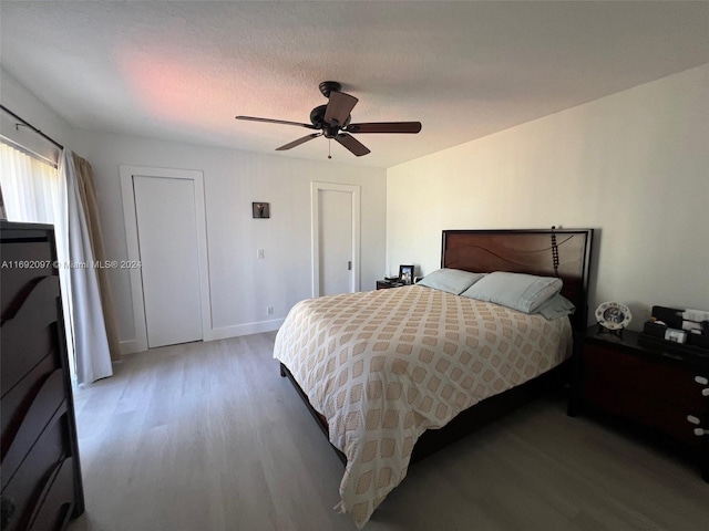 bedroom with hardwood / wood-style flooring, ceiling fan, and a textured ceiling