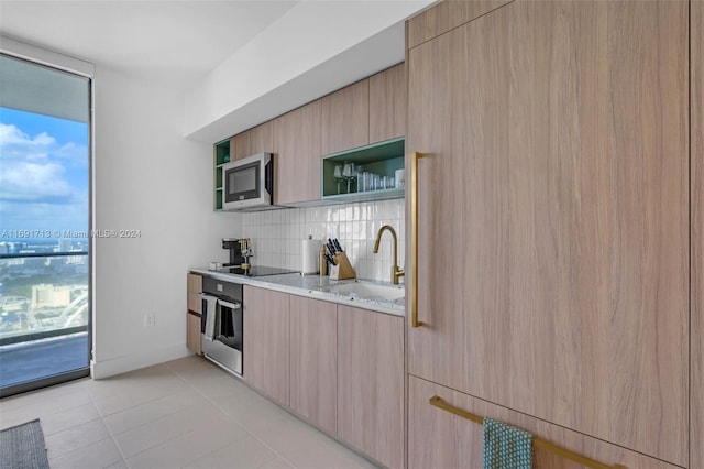 kitchen featuring sink, appliances with stainless steel finishes, tasteful backsplash, light brown cabinets, and light stone countertops