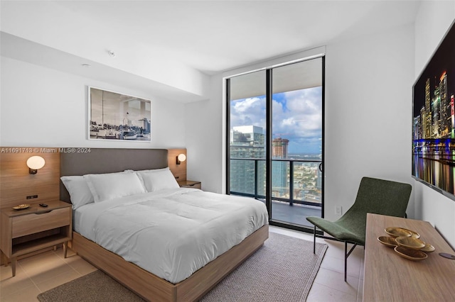 bedroom with a wall of windows, light tile patterned floors, and access to exterior