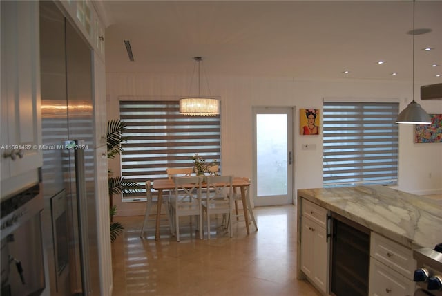 kitchen featuring white cabinetry, wine cooler, light stone counters, a notable chandelier, and decorative light fixtures