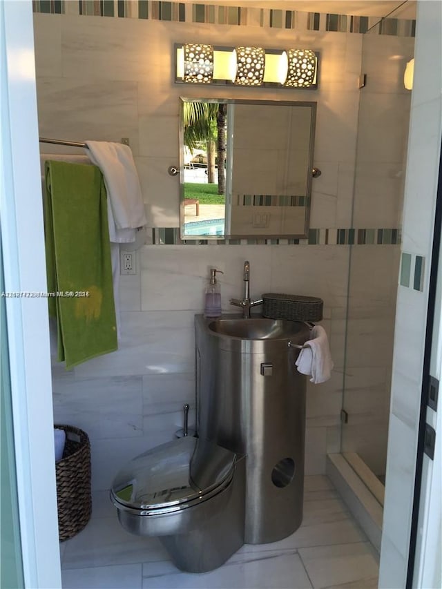 bathroom featuring tile patterned floors, a shower, toilet, and tile walls