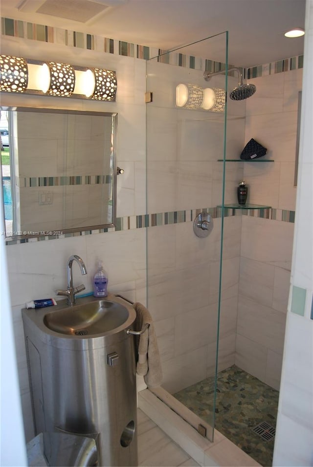 bathroom featuring decorative backsplash, sink, tiled shower, and tile walls