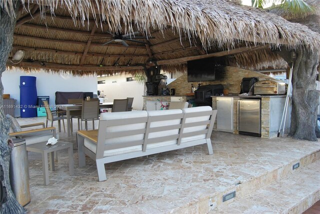 view of patio / terrace featuring outdoor lounge area, a gazebo, ceiling fan, and exterior kitchen