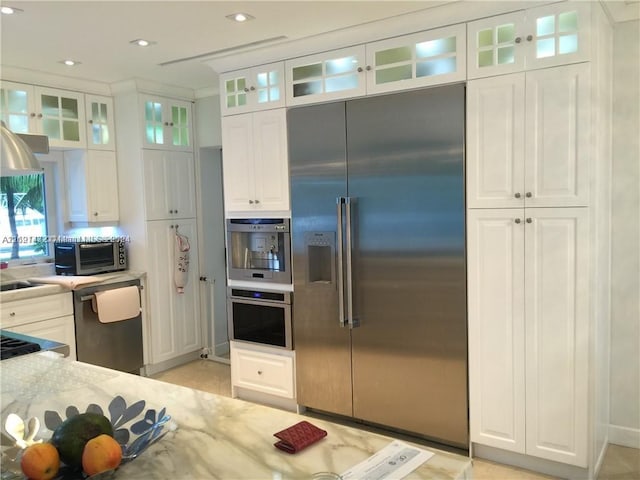 kitchen featuring white cabinets, stainless steel appliances, and light stone countertops