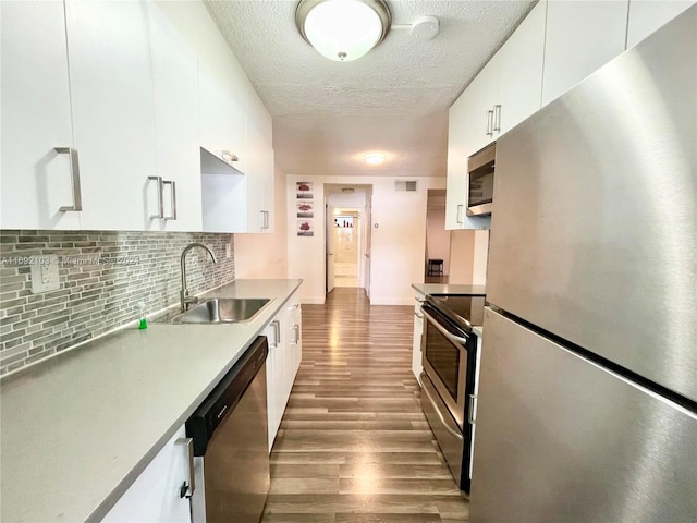 kitchen with hardwood / wood-style floors, a textured ceiling, sink, white cabinetry, and appliances with stainless steel finishes