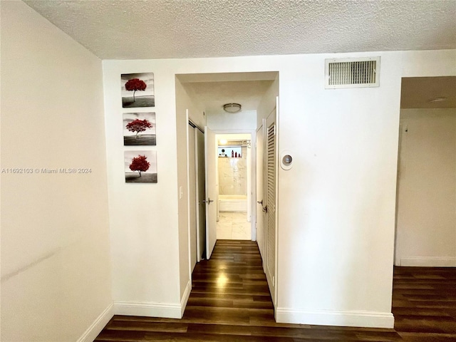 corridor featuring dark hardwood / wood-style flooring and a textured ceiling