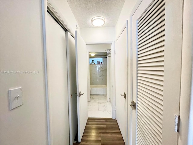 hall with a textured ceiling and dark hardwood / wood-style flooring