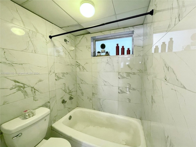 bathroom with toilet, tile walls, and tiled shower / bath combo