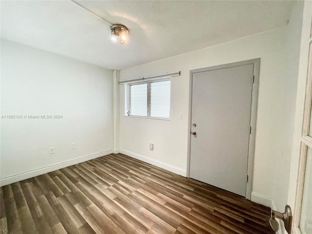 empty room with wood-type flooring and a textured ceiling