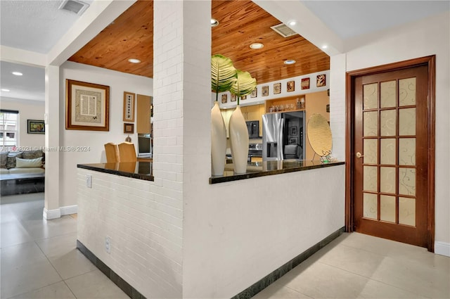 interior space featuring wooden ceiling and stainless steel fridge